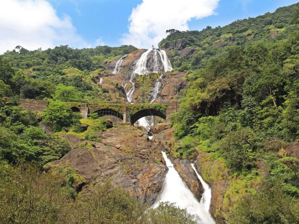 a beautiful view of train passing by dudhsagar waterfal
